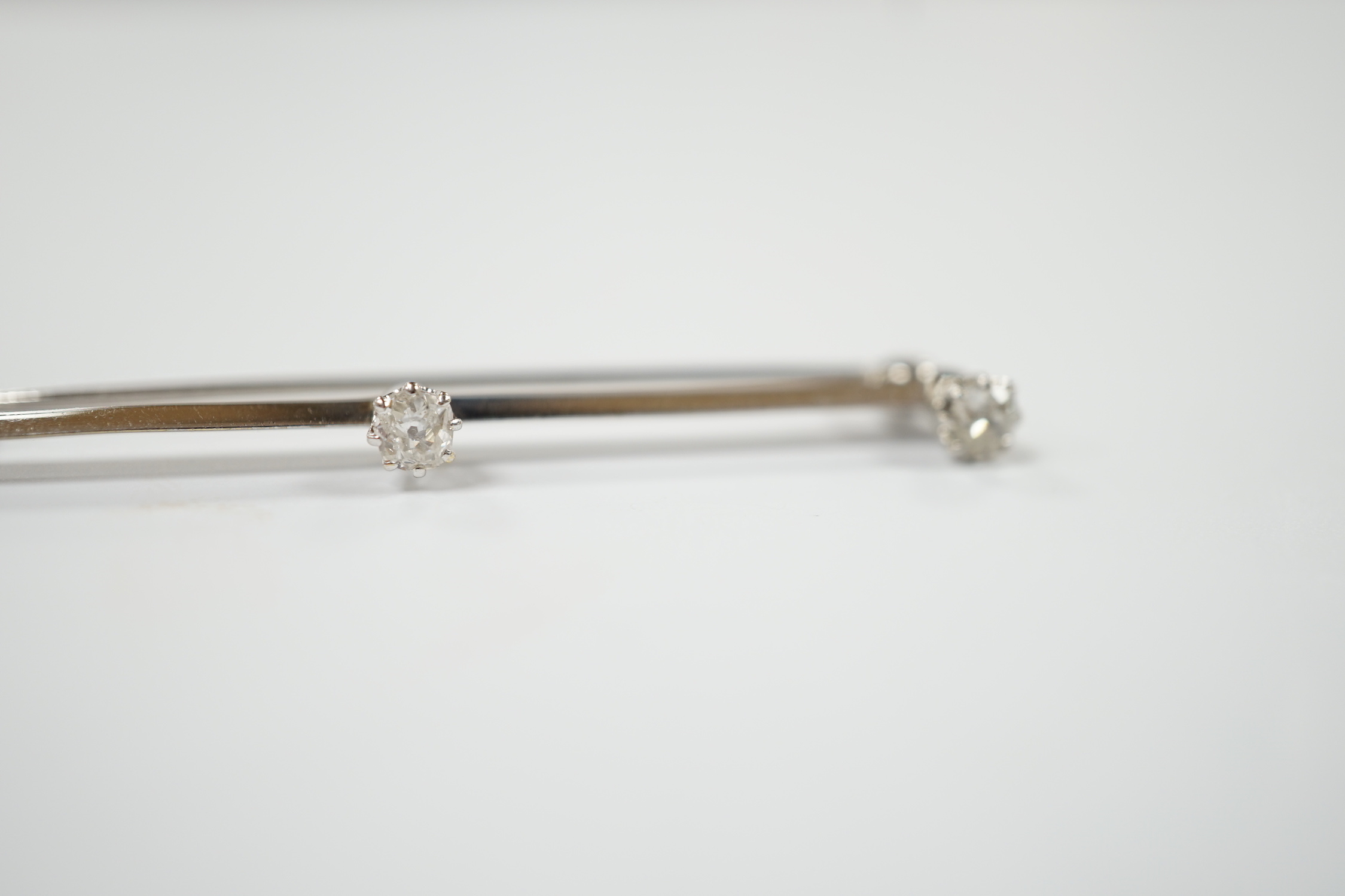 A white metal and three stone diamond set bar brooch, 56mm, gross weight 3.4 grams.